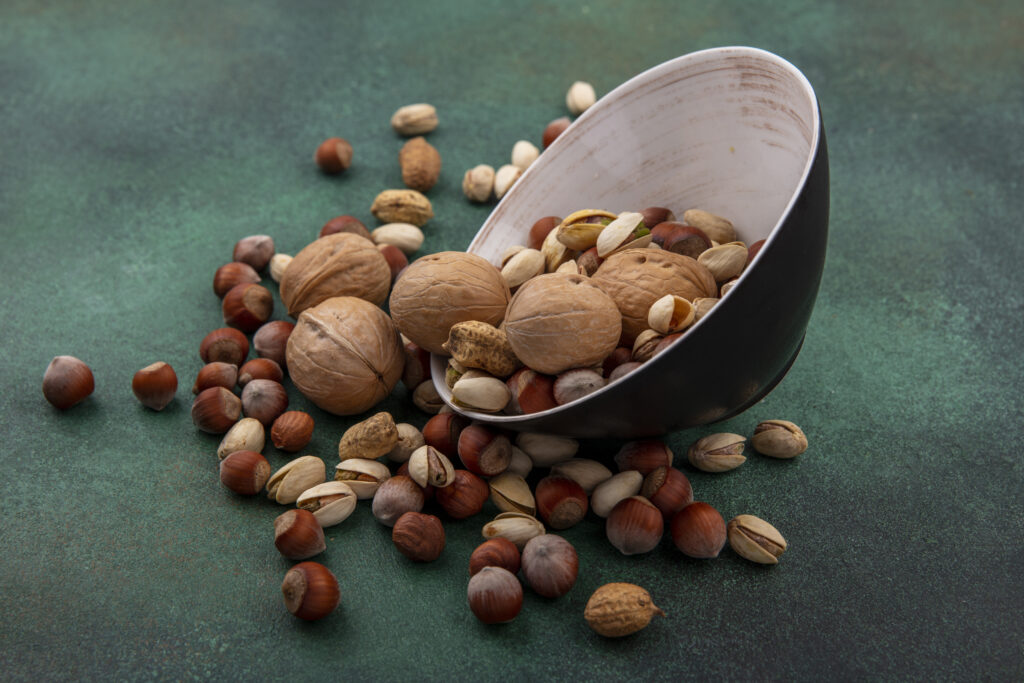 7 Best Foods That Boost Mood Naturally 5 side view mix nuts walnuts pistachios hazelnuts peanuts bowl green surface